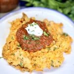 Doritos chicken casserole on a plate with salsa and sour cream.