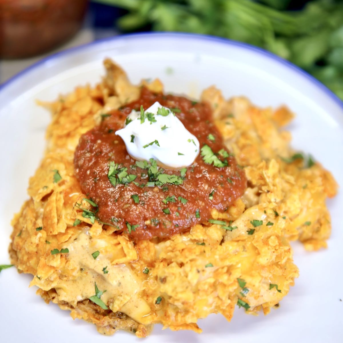 Doritos chicken casserole on a plate with salsa and sour cream.