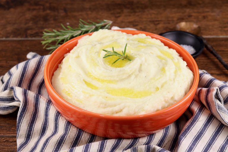 Bowl of mashed potatoes with melted butter and rosemary