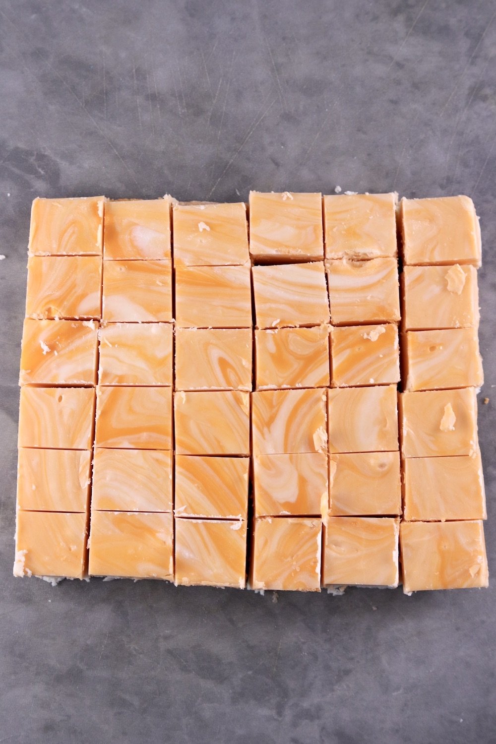 Creamsicle Fudge cut into squares on a gray cutting board