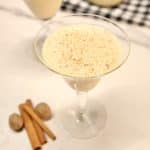 Glass of egg nog, cinnamon sticks, whole nutmeg.