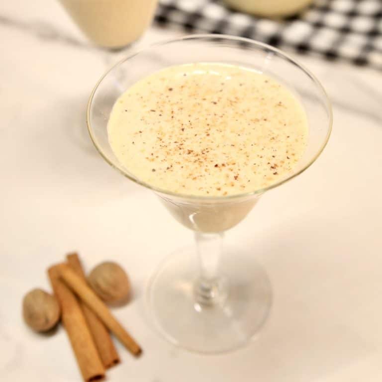 Glass of egg nog, cinnamon sticks, whole nutmeg.
