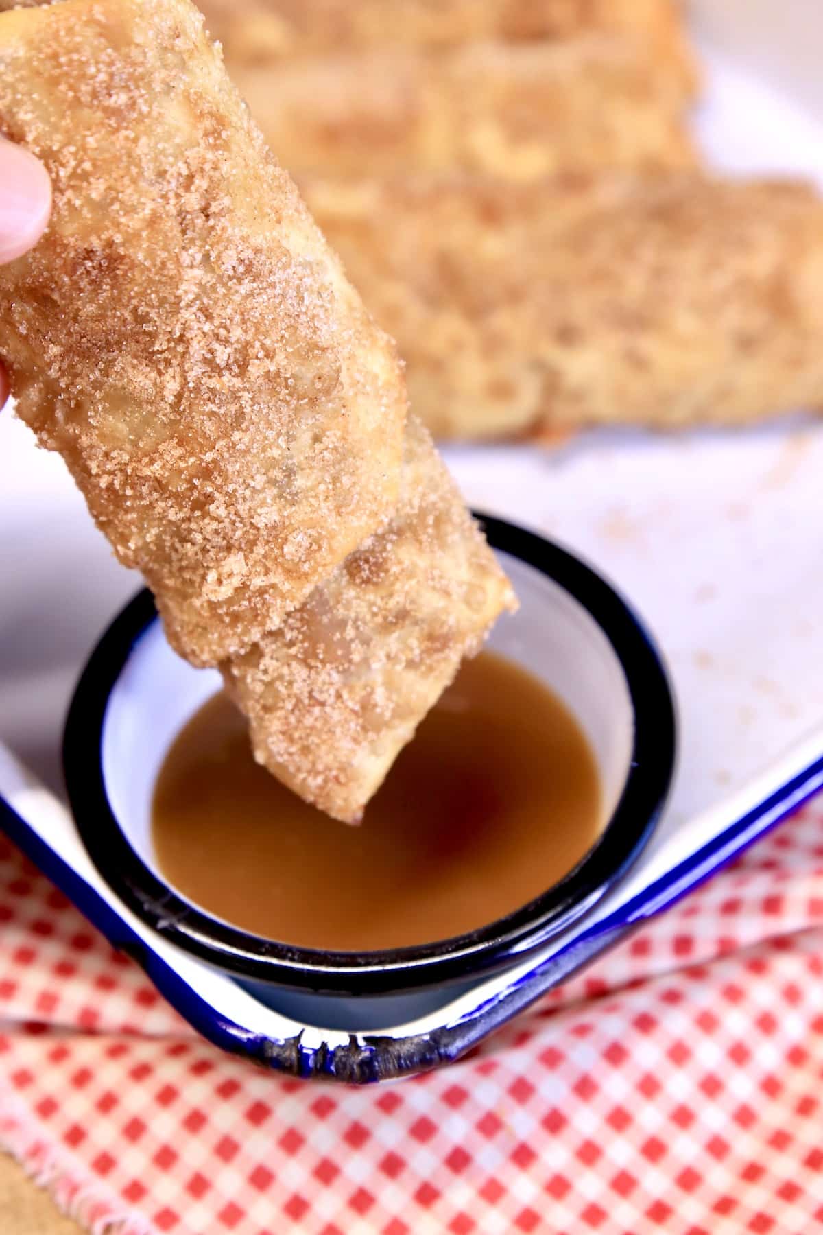 Dunking apple pie egg roll in caramel sauce.