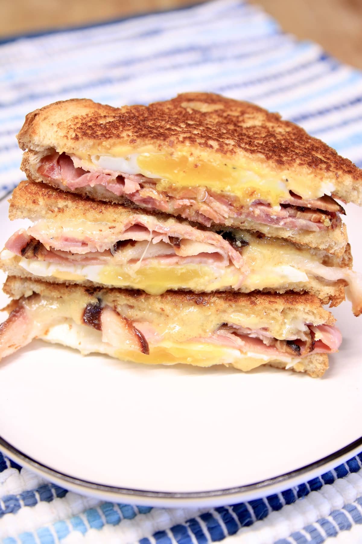 Stack of ham, egg and swiss sandwiches, cut in half.