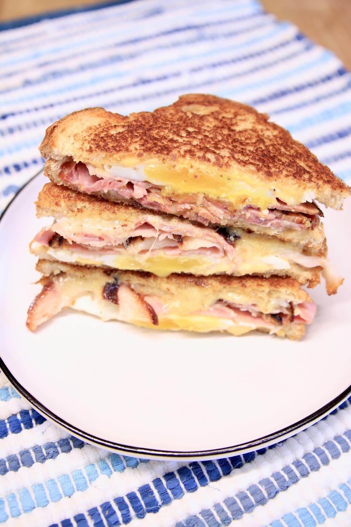 Toasted egg sandwiches, cut in half on a plate. 3 stacked.