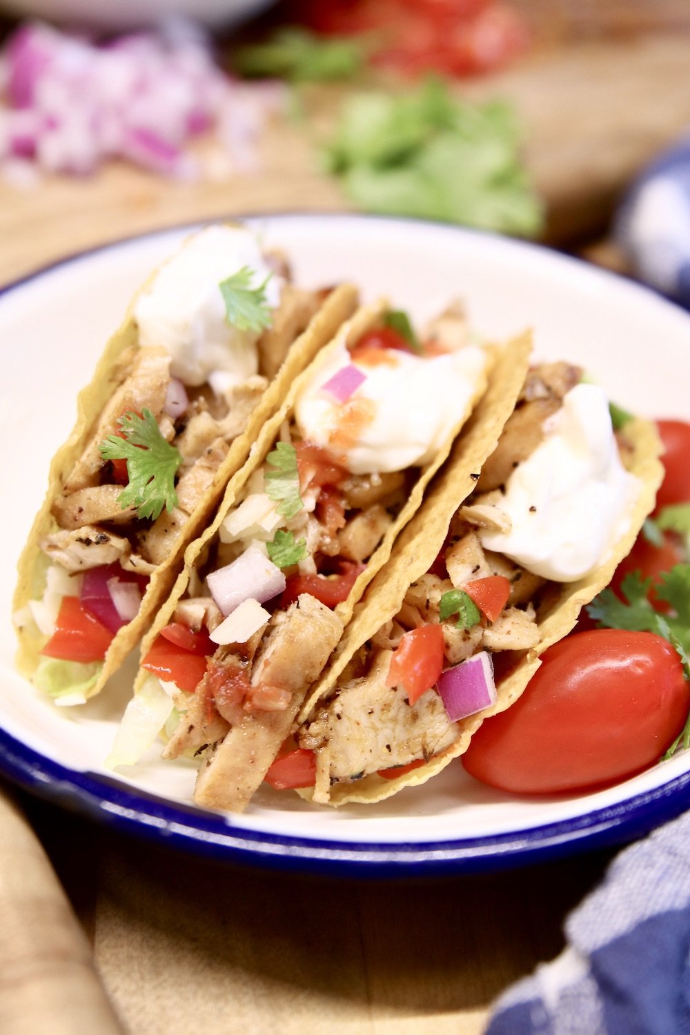 plate of 3 chicken tacos with sour cream and salsa