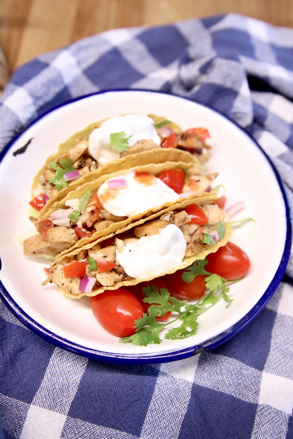 plate of 3 chicken tacos on a blue check towel