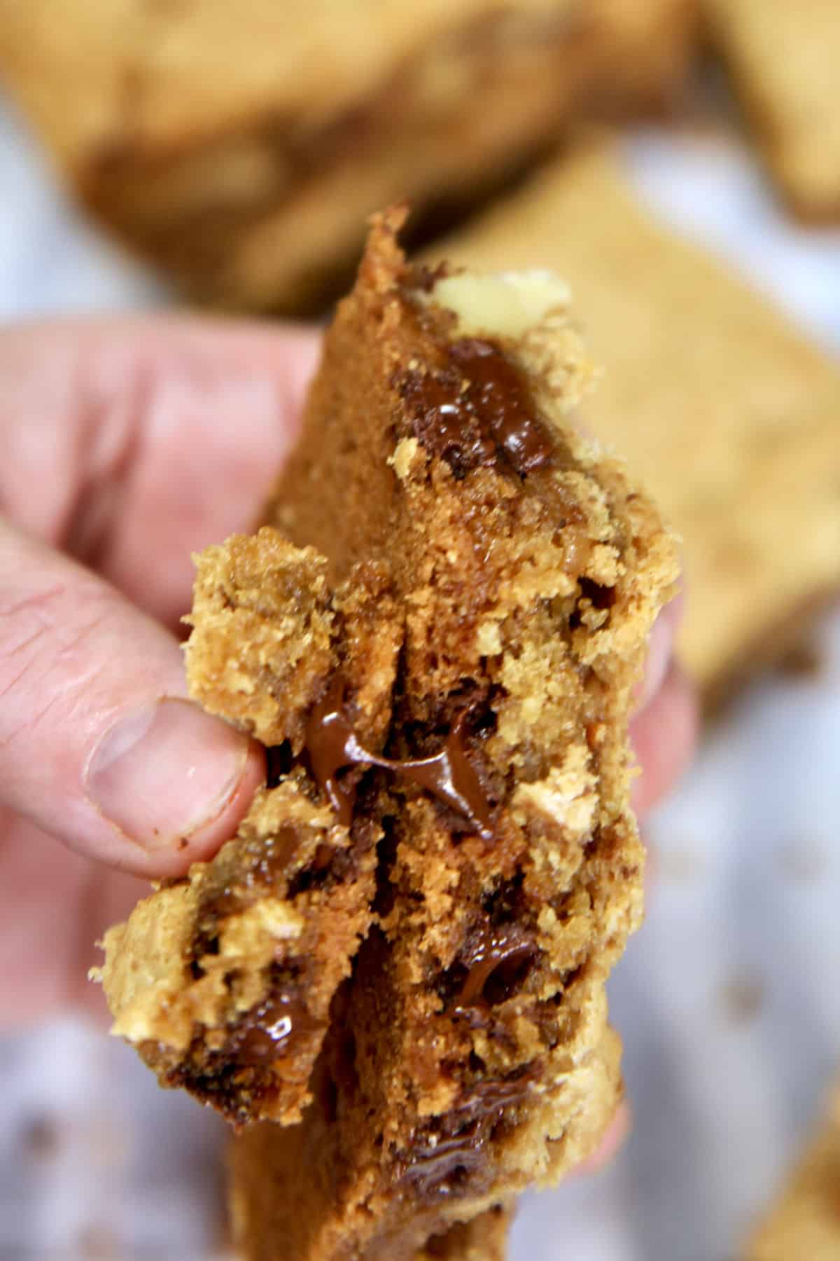 Cookie bar broke in half to show melted chocolate held in hand.
