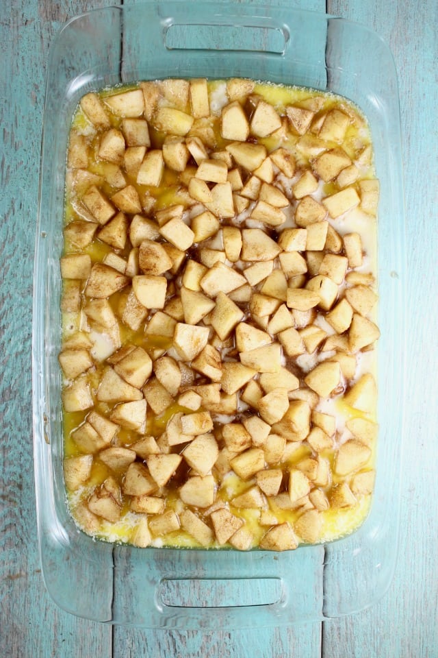 Diced apples and cinnamon in a pan over cobbler batter.