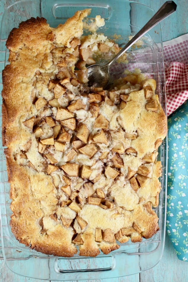 Apple cobbler in a 9 x 13 pan, spoon with one serving missing.