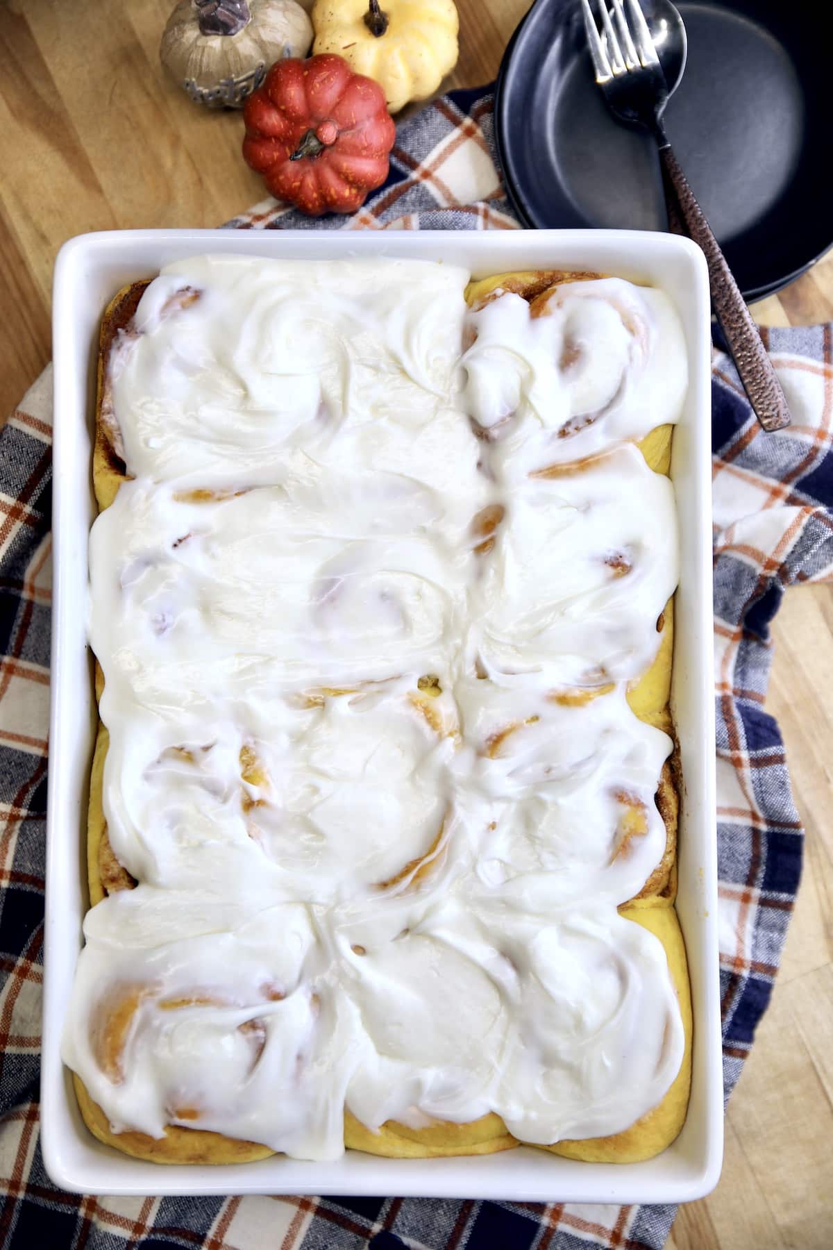 Pan of pumpkin cinnamon rolls with cream cheese icing.