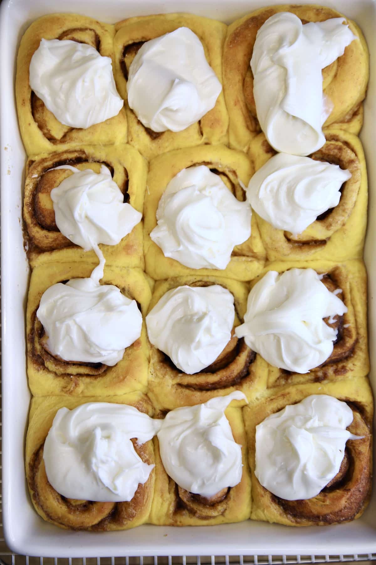 Pumpkin cinnamon rolls with dollops of cream cheese icing.
