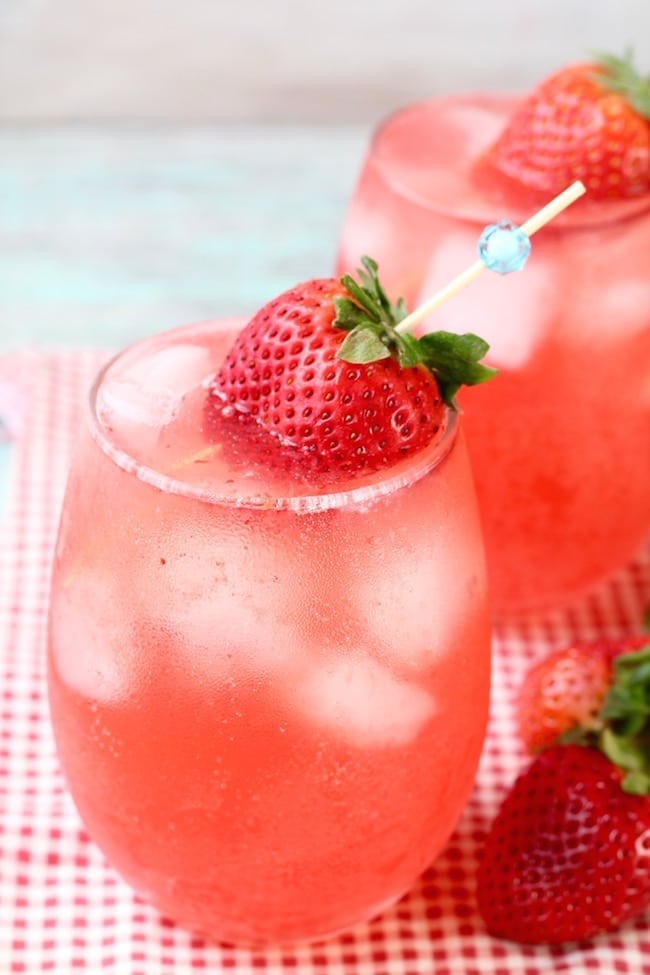 Strawberry Wine Punch over ice in a stemless wine glass garnished with a strawberry