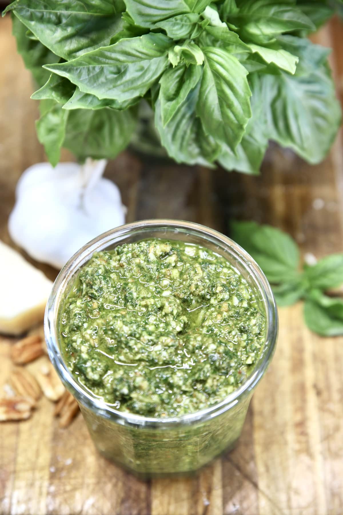 Basil pesto in a jar with fresh garlic and basil in a jar.