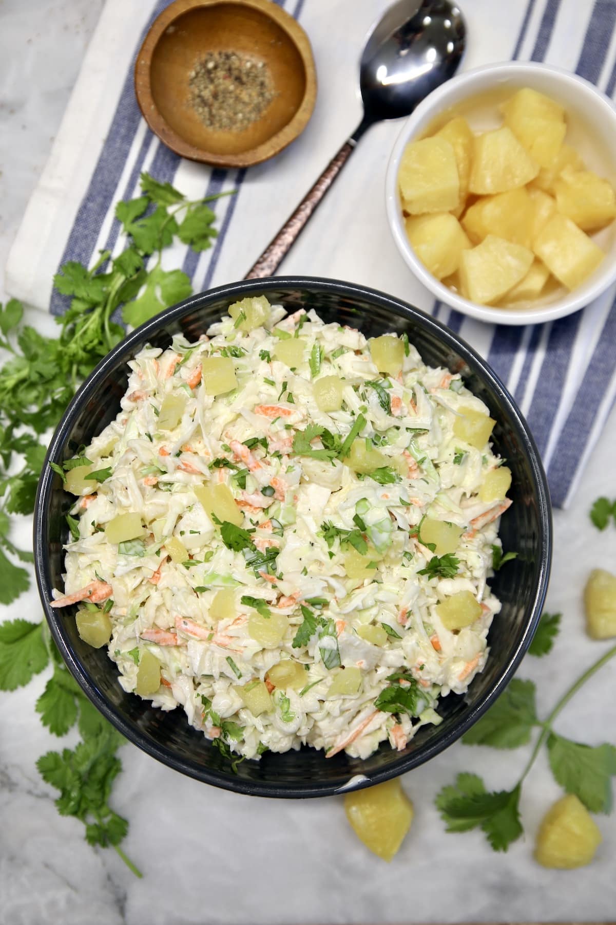 Pineapple coleslaw with cilantro. Bowl of pineapple coleslaw, small bowl of pineapple, cilantro.