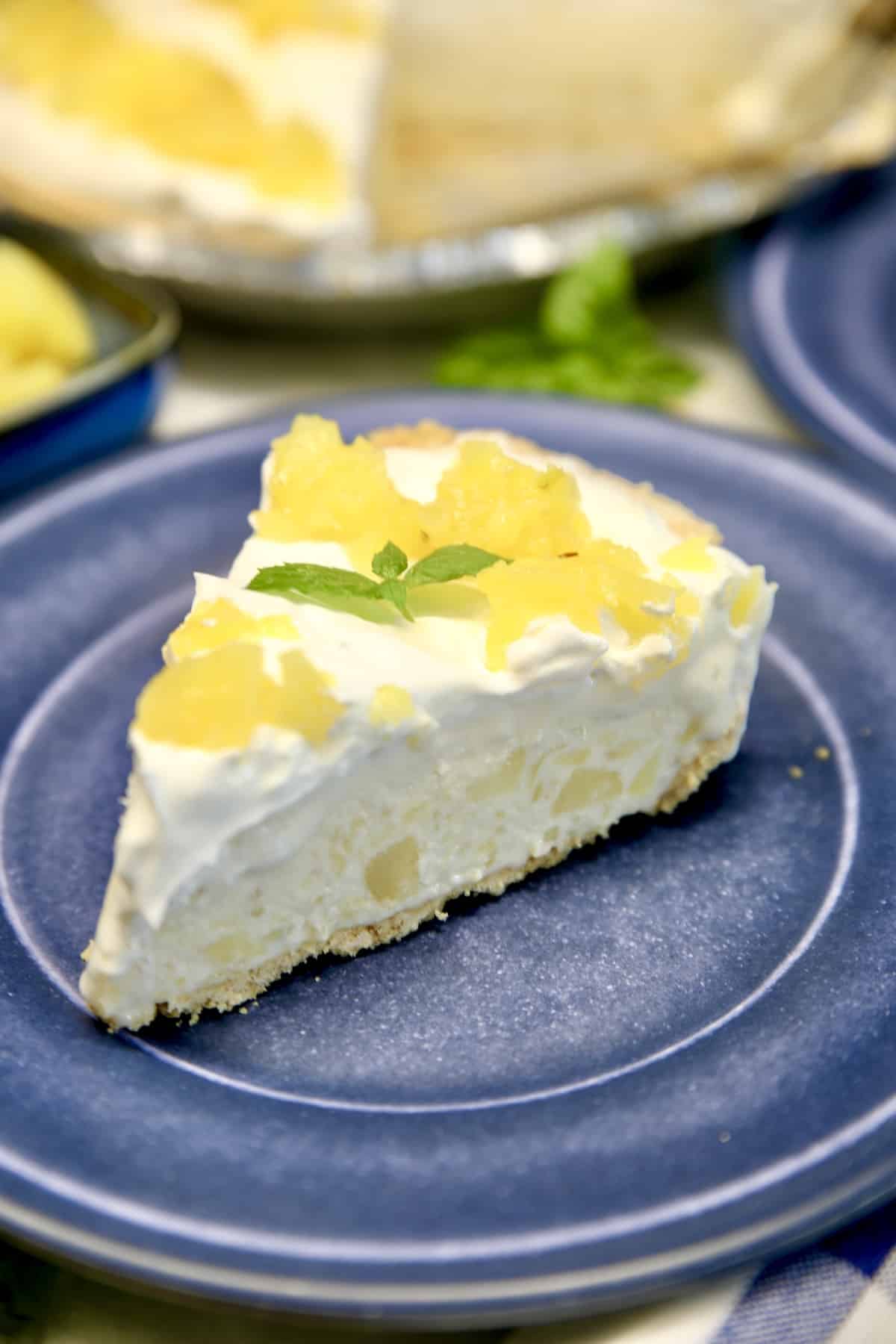 Frozen Pineapple Pie with creamy filling and graham cracker crust. Frozen Pineapple Pie slice on a blue plate.