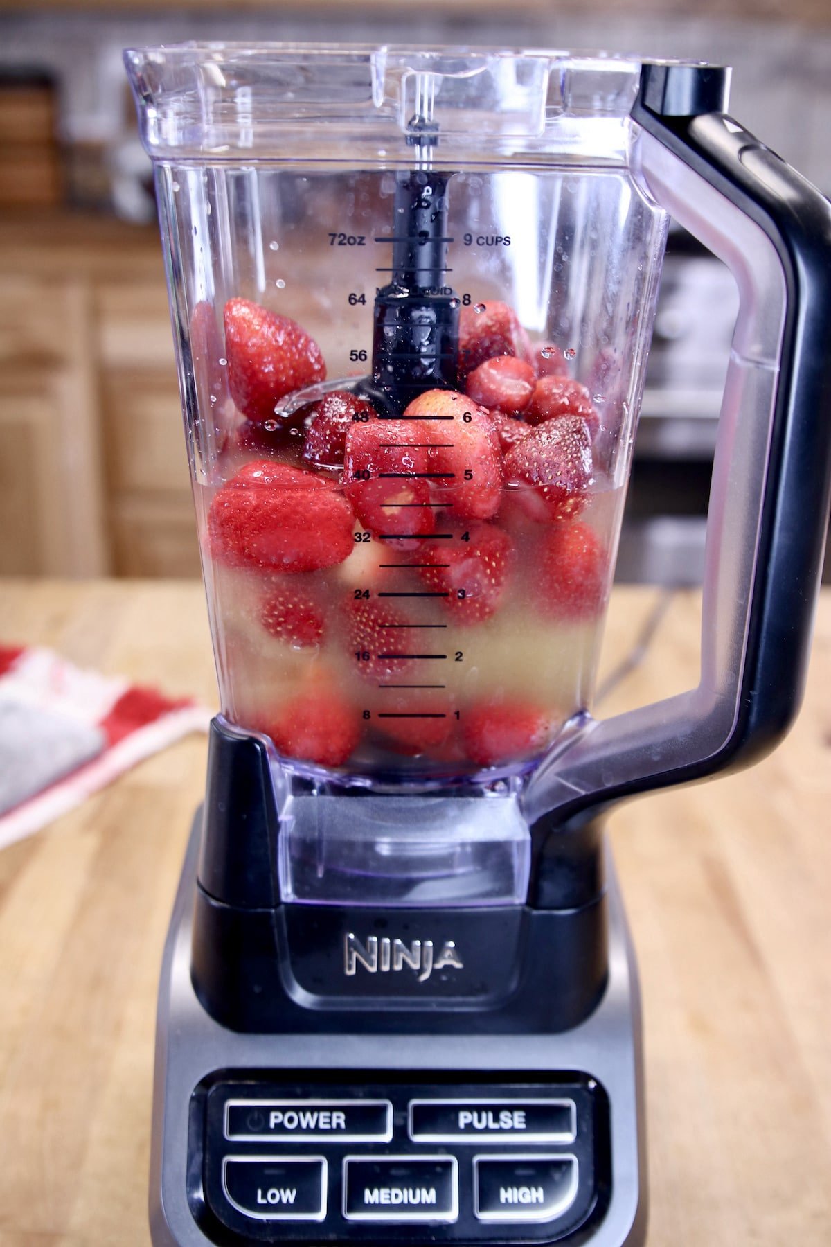 blender with frozen strawberries and cocktail ingredients.