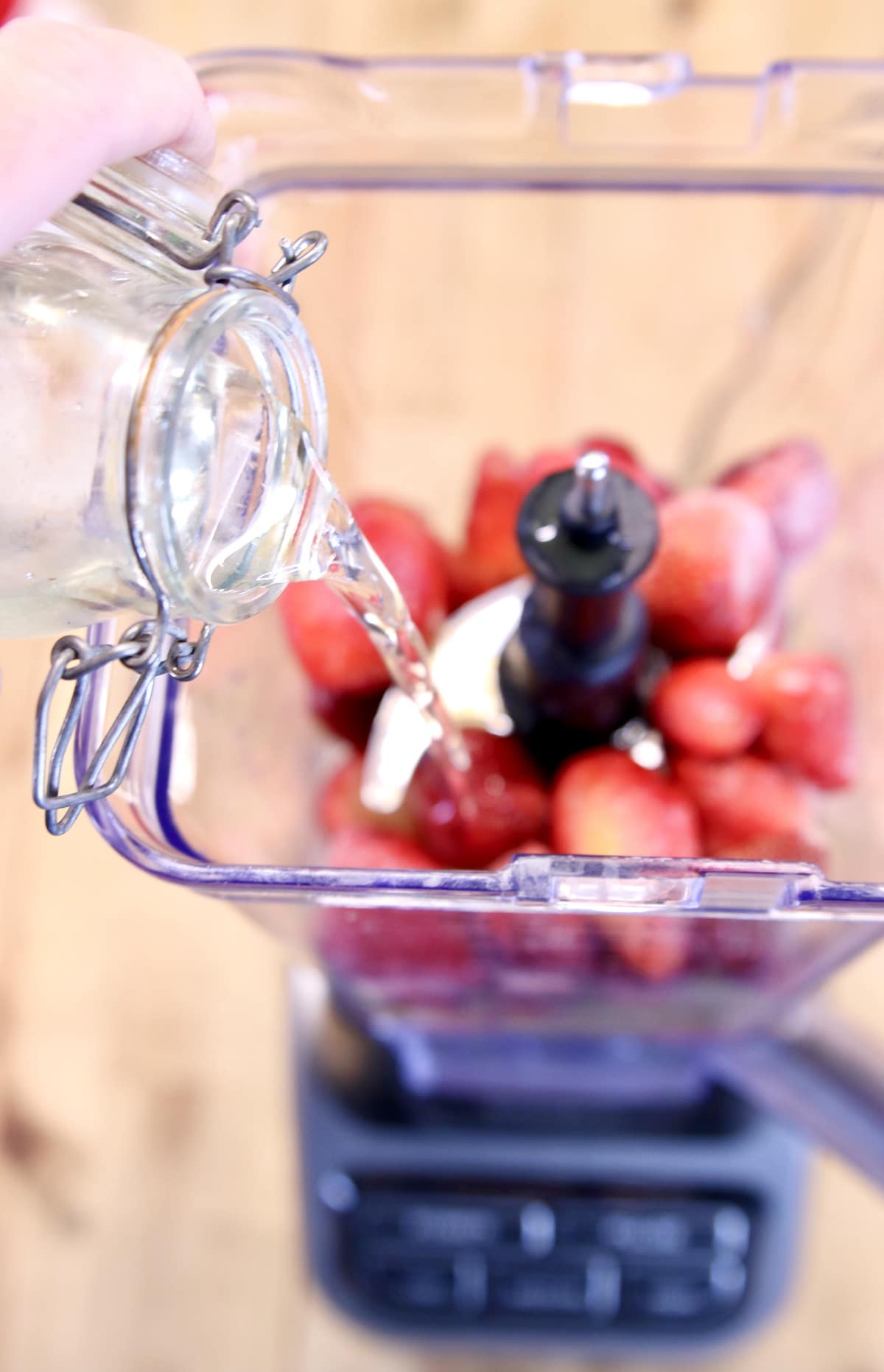 pouring simple syrup into blender with strawberries