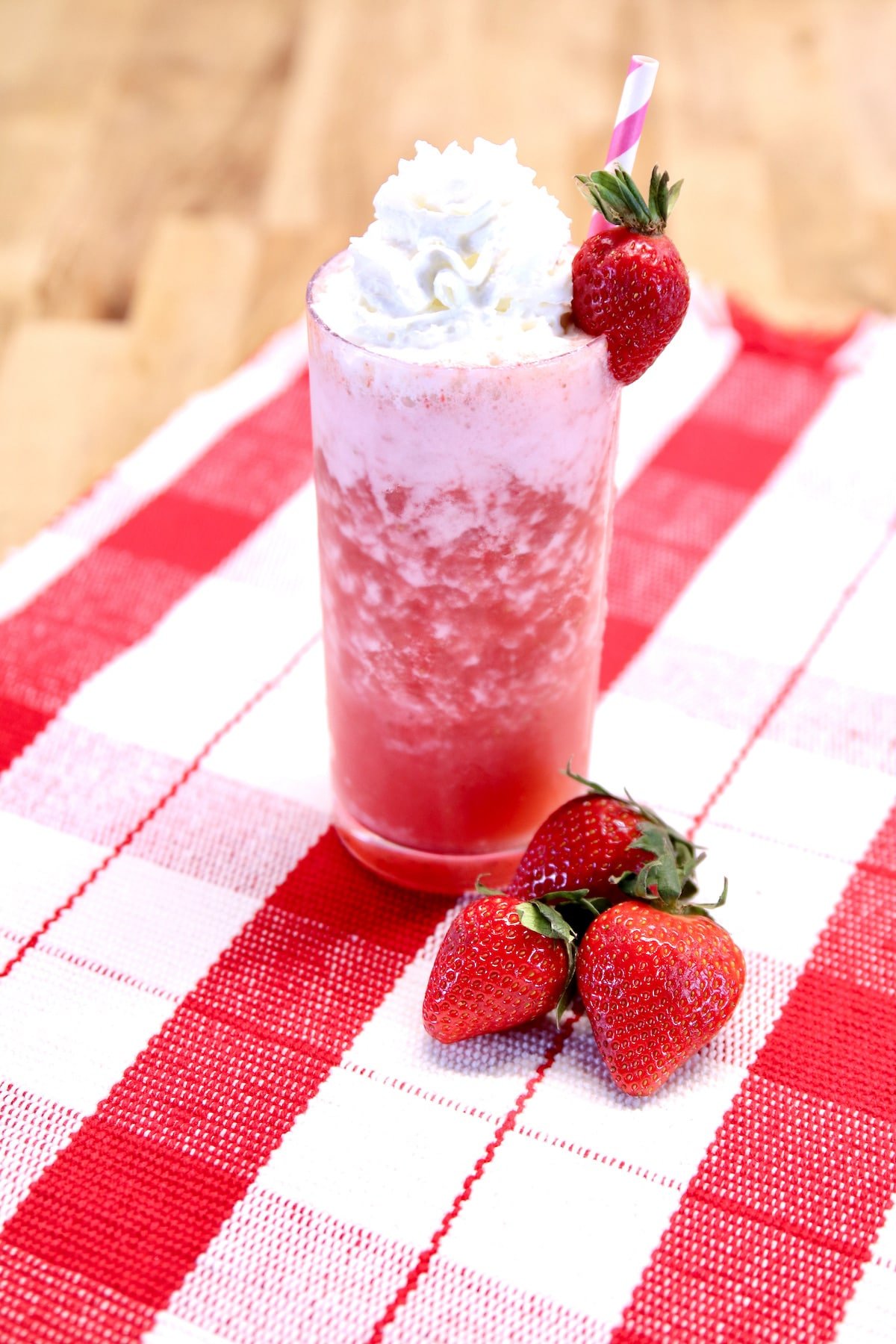 strawberry cocktail topped with whipped cream and strawberry garnish.