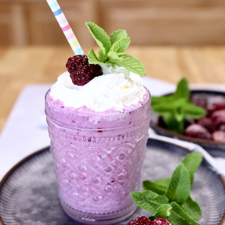 blackberry milkshake with whipped cream, blackberry and mint garnish.