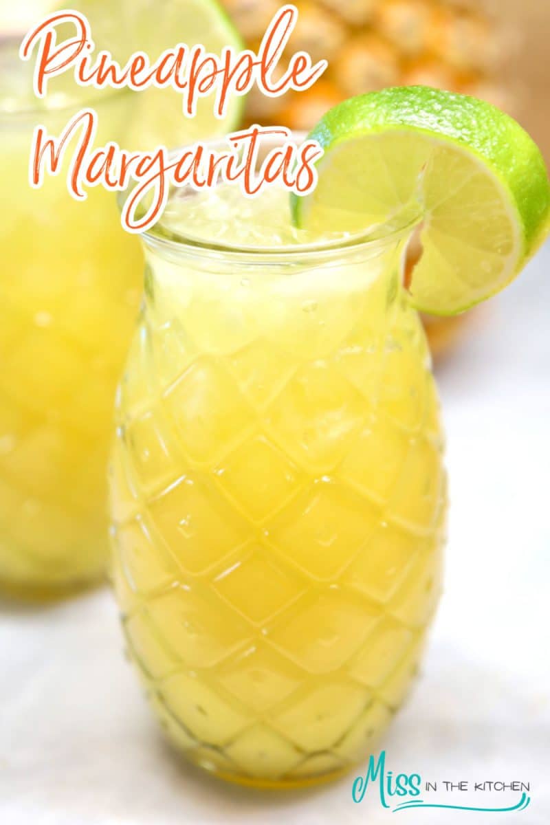 Pineapple Margaritas in tiki glass with lime wheel. Text overlay.