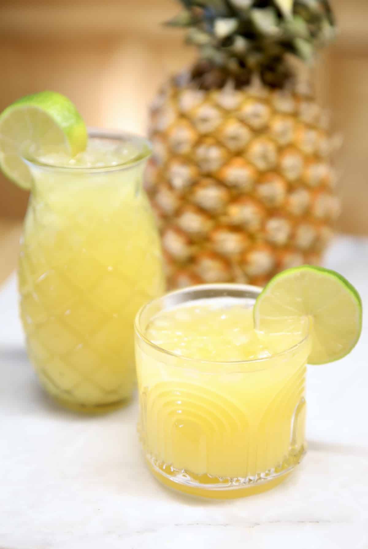 Easy pineapple margaritas. Pineapple Margaritas in a pineapple glass & tiki glass, pineapple in background.