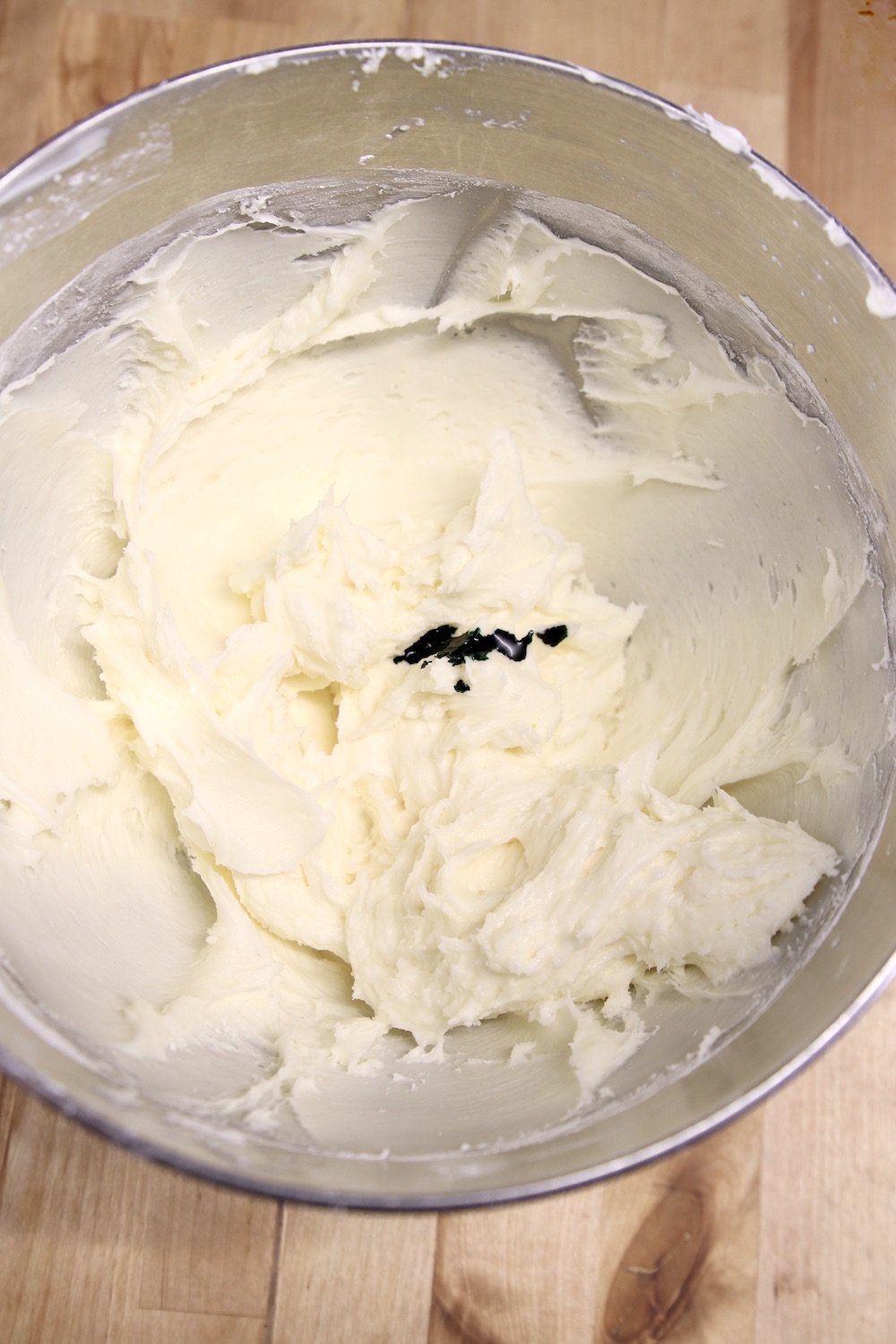 Drops of green food coloring added to bowl of cream cheese icing