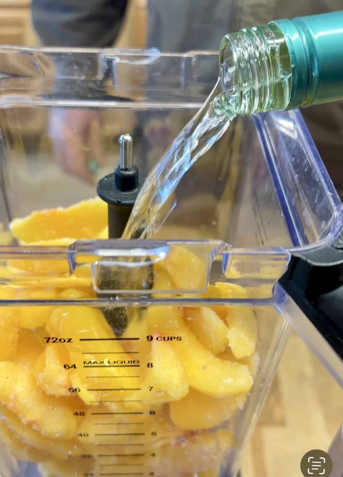 Pouring wine into a blender with peaches.