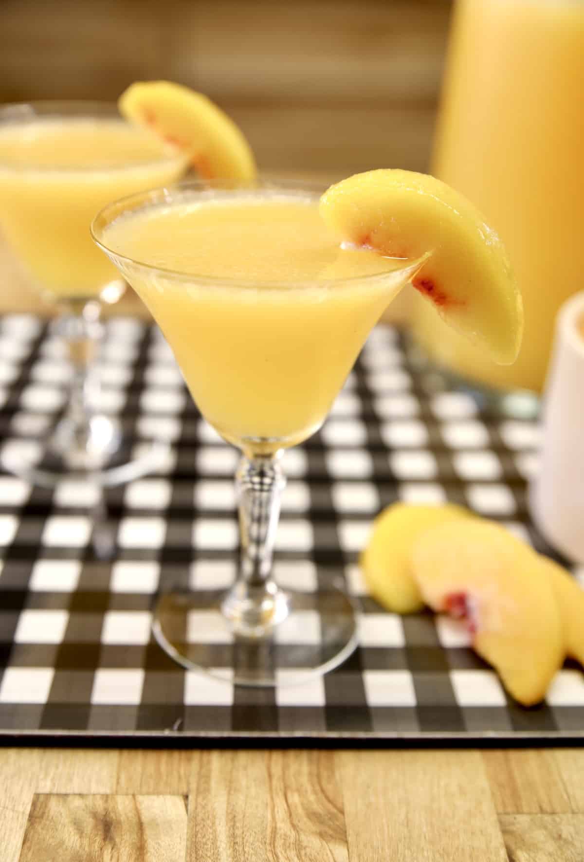 2 glasses with peach moscato punch, sliced peaches.