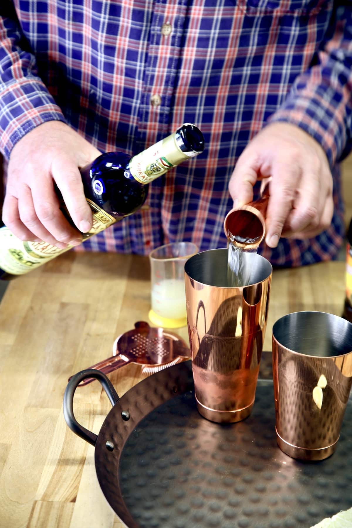 Pouring tequila into a cocktail shaker.