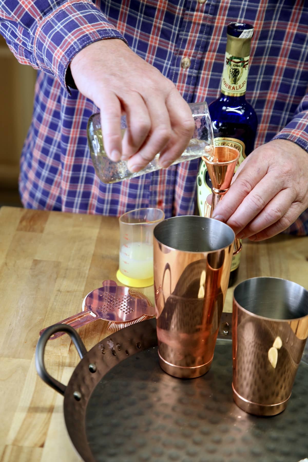 Pouring simple syrup into a cocktail shaker.