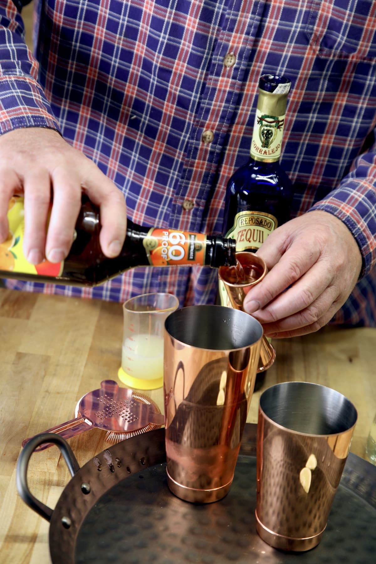 Pouring triple sec into a cocktail shaker.