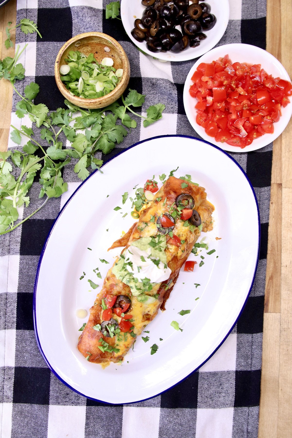 plate with chicken enchilada with sour cream, tomatoes, cilantro.