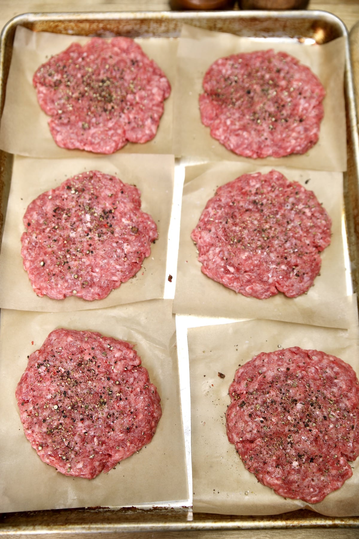 6 Burger patties on parchment squares.