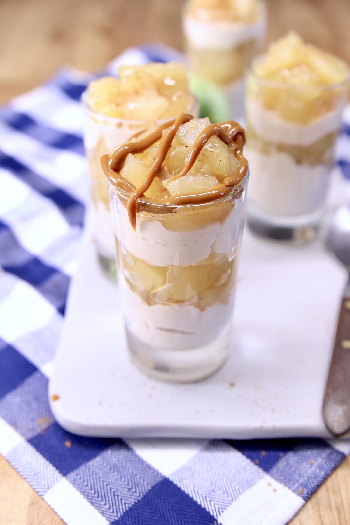 Caramel drizzled over glass of cinnamon apple cheesecake