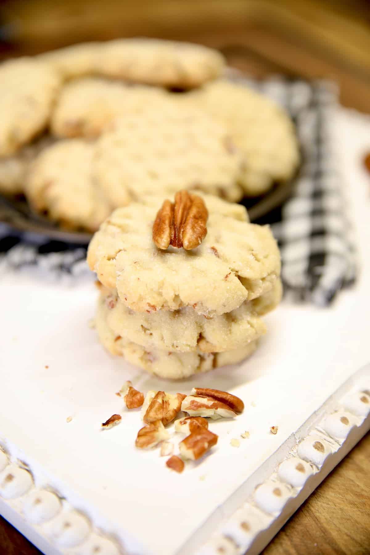 Stack of pecan sandies cookies with pecan half on top.