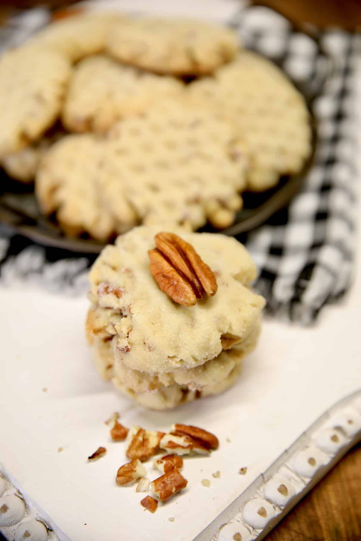 Stack of pecan sandies cookies with platter of cookies.