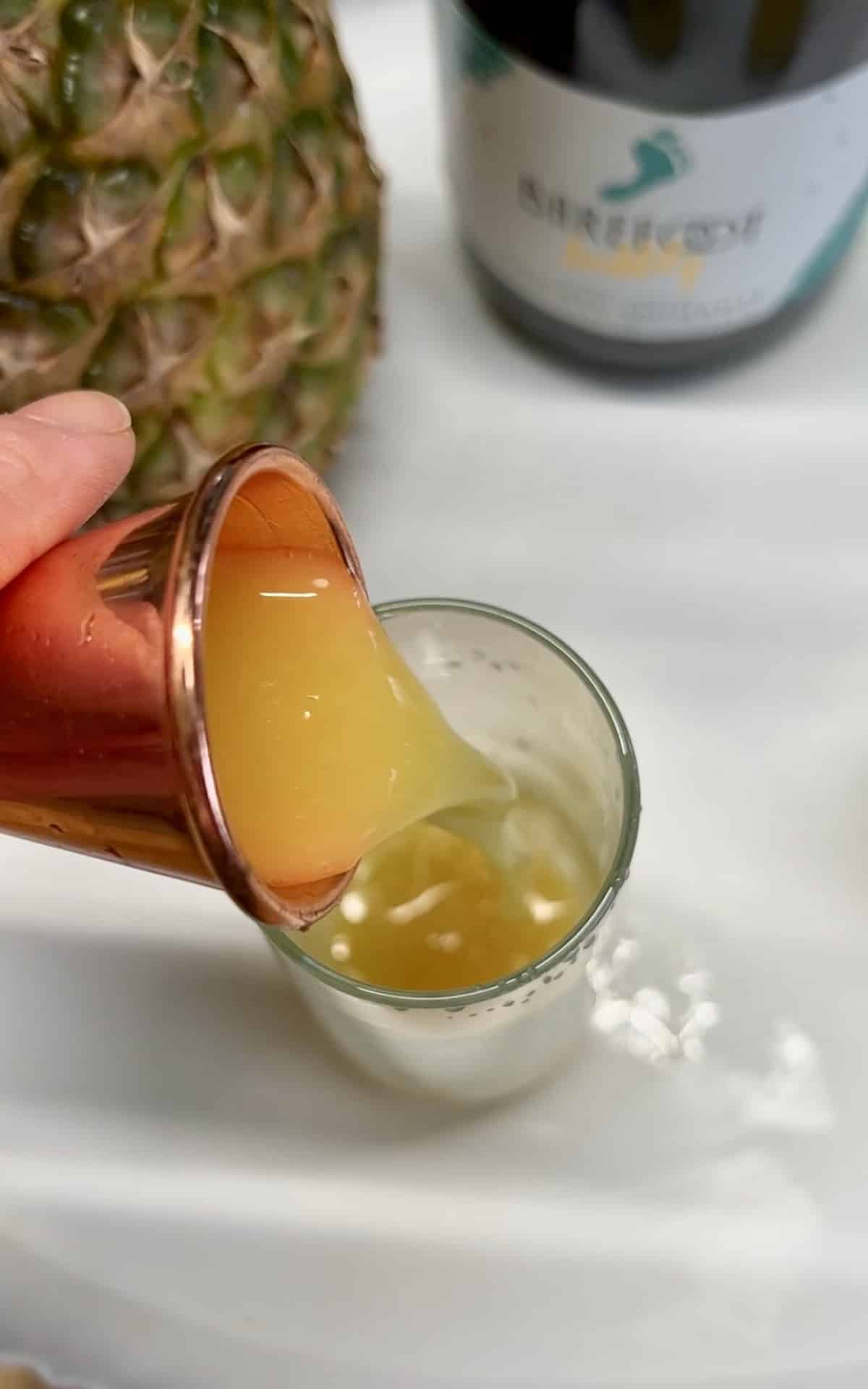 Jigger adding orange juice to champagne glass.