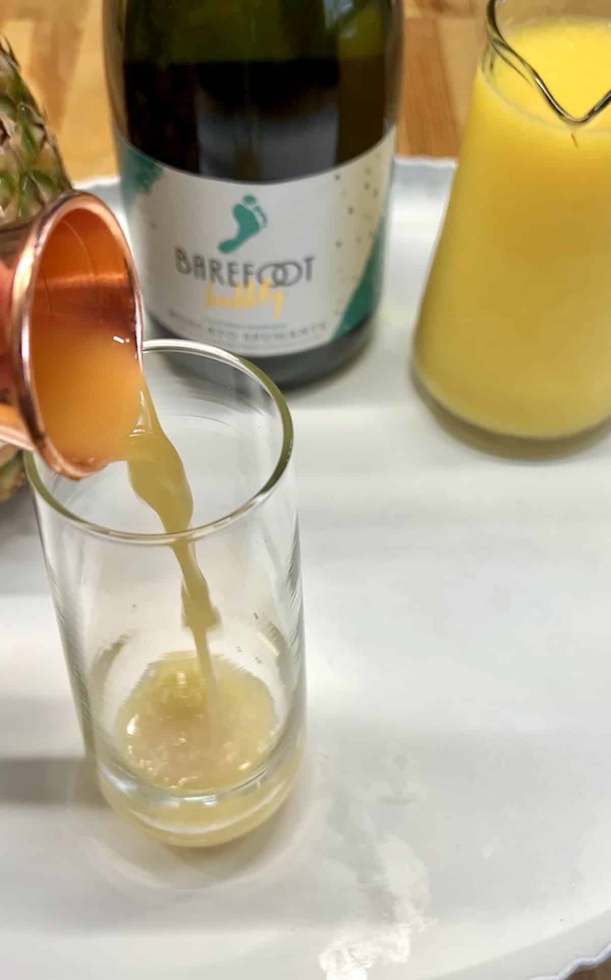 Pouring pineapple juice into cocktail glass.