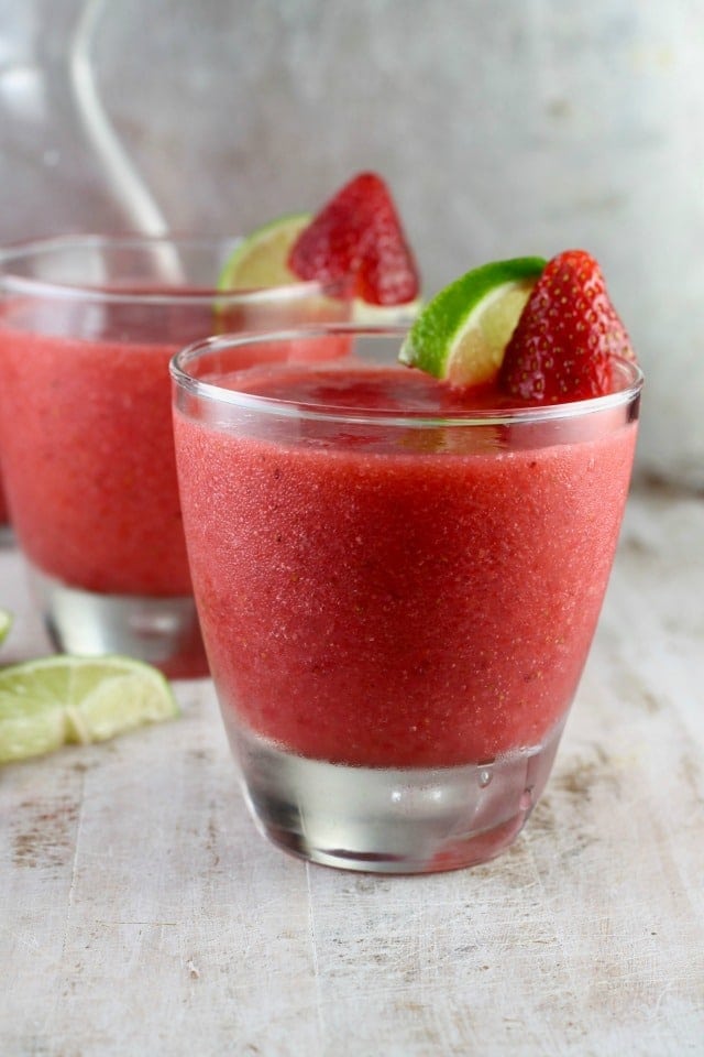 2 frozen Strawberry Daiquiri frozen cocktails with strawberry and lime garnish.