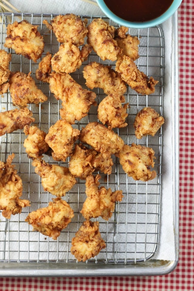 Fried chicken bites on a wire rack with bowl of bbq sauce.