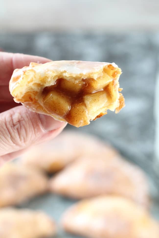 Hand holding a Fried Apple Hand Pie with the filling showing