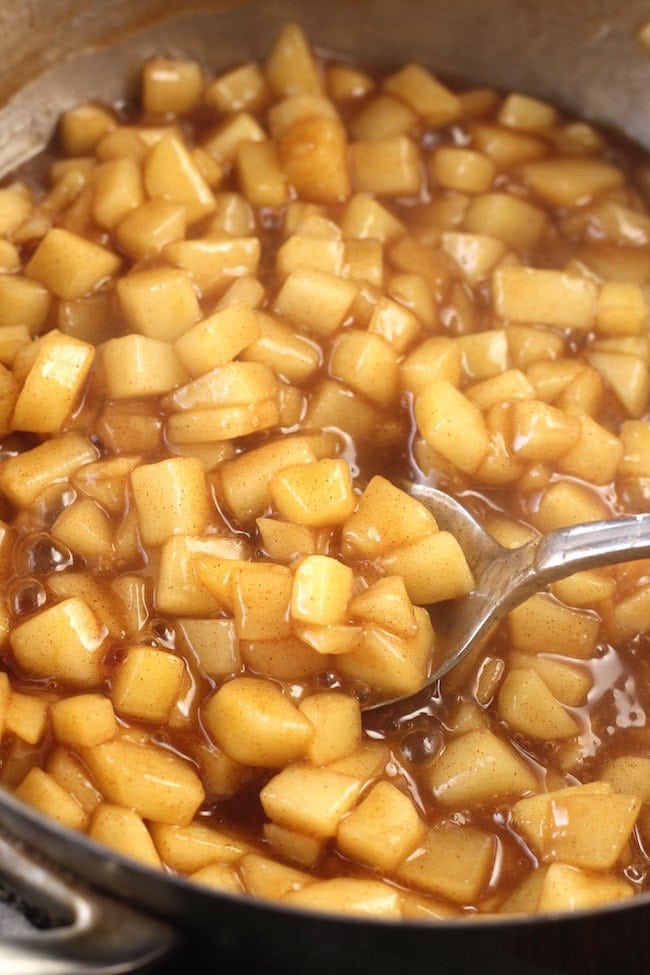 Cooked diced apples with cinnamon sugar and nutmeg with a spoon