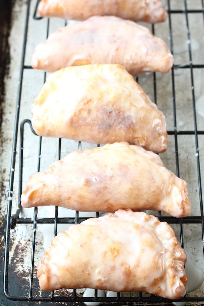 Glazed Fried Apple Hand Pies drying on a wire rack on a baking sheet