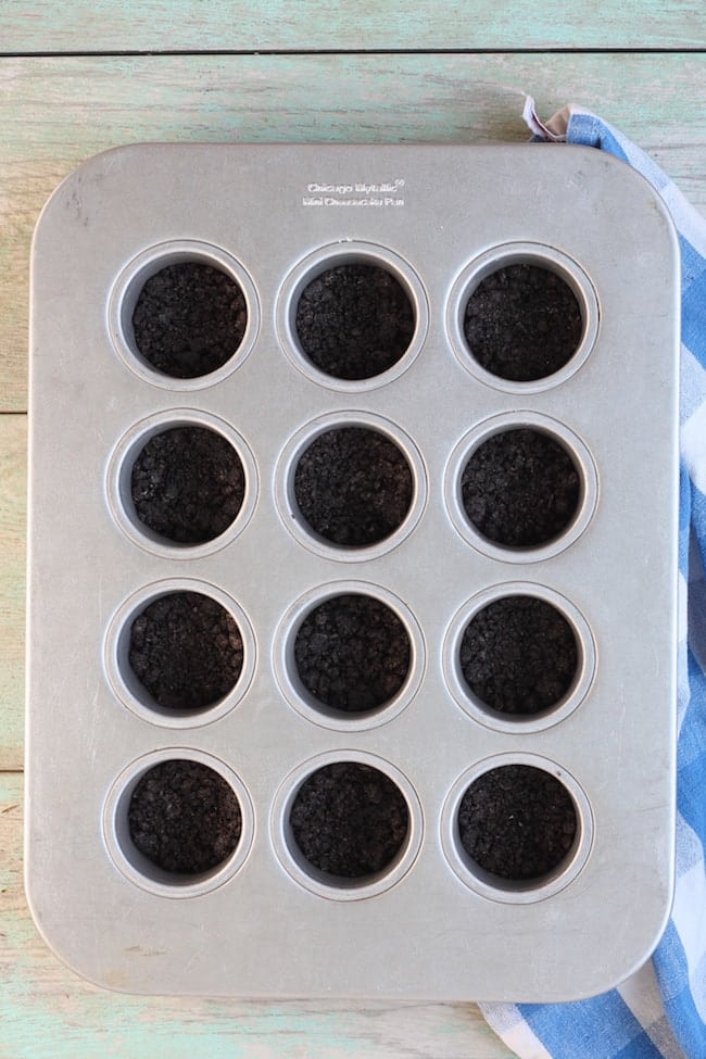 Oreo Crust in mini cheesecake pan for Mini Cherry Cheesecakes Recipe