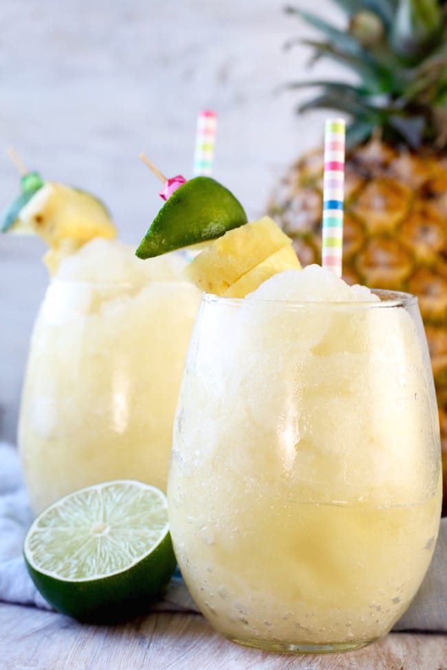 Pineapple Limeade Frozen Slush with a fresh lime half, pineapple in background