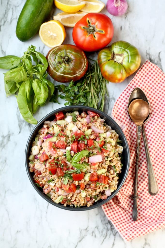 Farro with tomatoes, basil, and cucumbers, Fresh tomatoes, cucumber lemon and red onion in the background