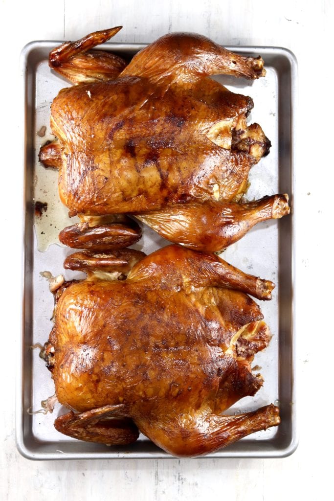 Two whole smoked chickens on a baking sheet