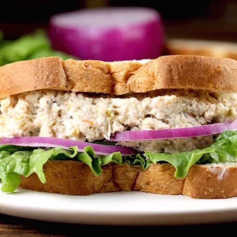 Closeup of turkey salad sandwich with lettuce and red onions.