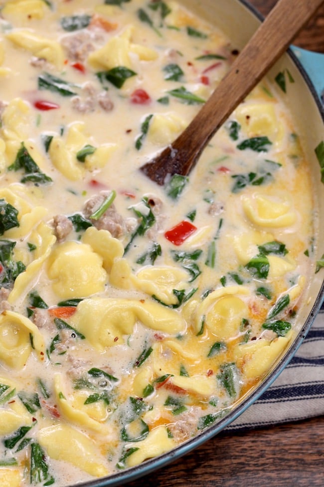 Creamy Tortellini Soup with sausage in a pan with spoon.
